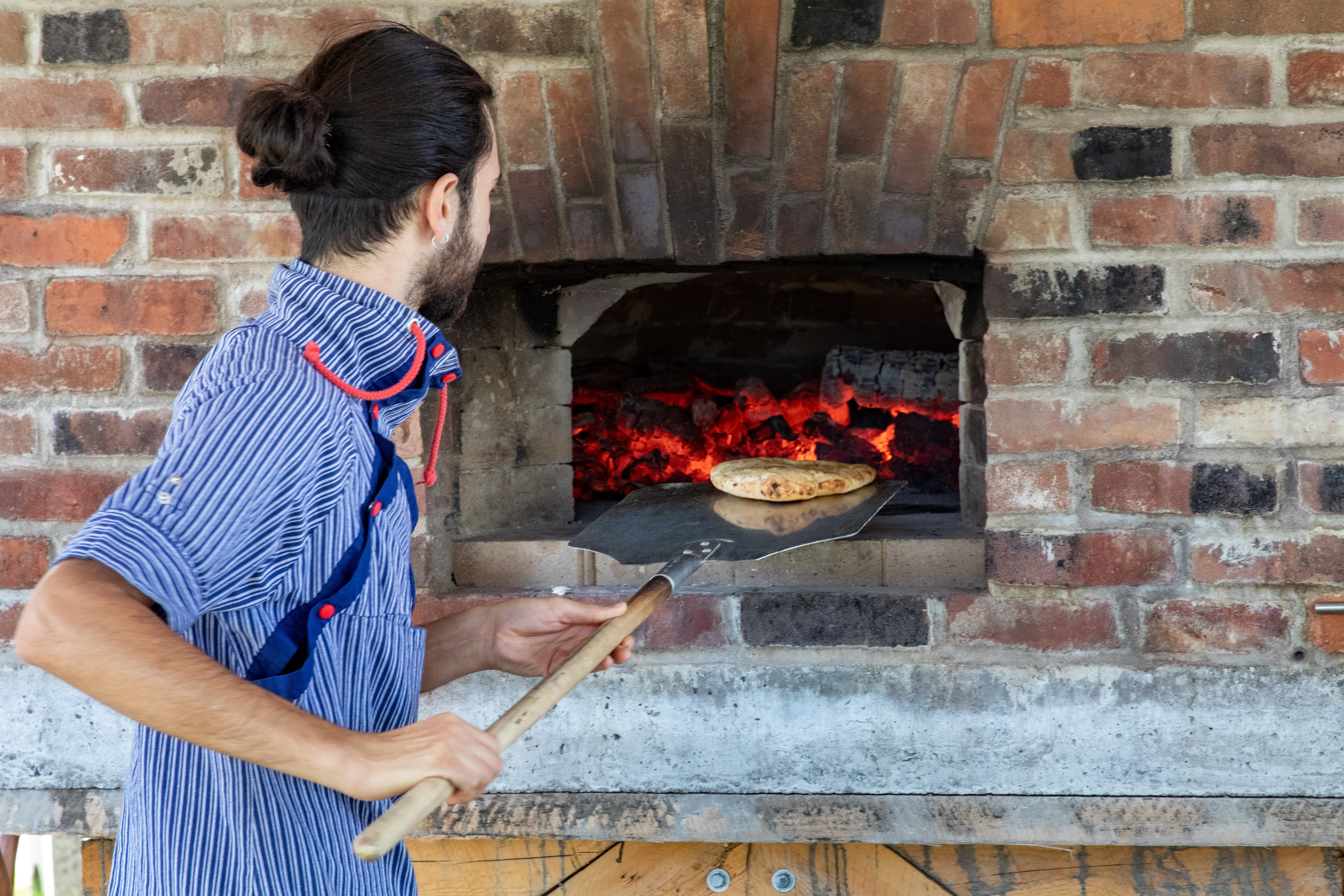 Baker loading outdoor wood-fired oven