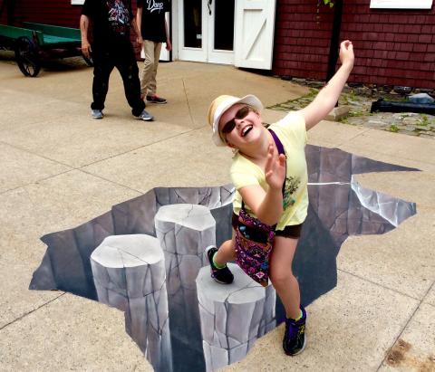 child standing on 3-dimensional chalk art on the street