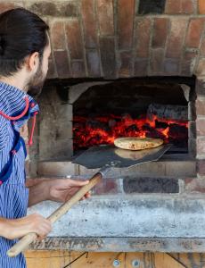 Baker loading outdoor wood-fired oven