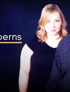 "the melberns" cover image: a middle-aged white woman and man stand in the forefront, both wearing black, posing for the camera