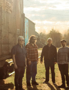 "The Voodoo Charmers": Four white men stand outside a train cab in lower Wolfville