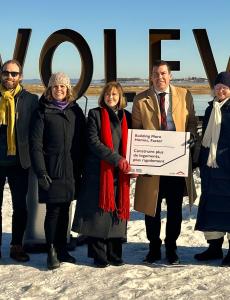 A crowd stands in front of the Wolfville sign.