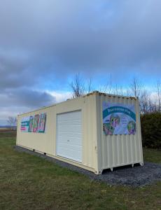 Shipping container placed on an open field with banners that show the upcoming Recreation Hub with a cloudy background.